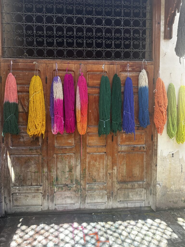 Different swatches of brightly dyed fabric hanging in the market in Fez, Morocco